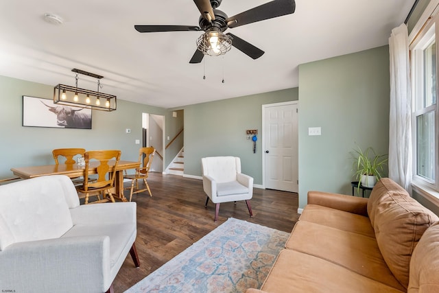 living area with stairway, wood finished floors, a ceiling fan, and baseboards