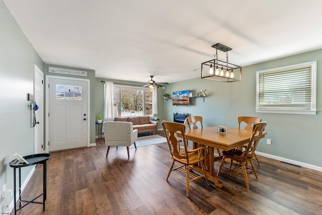 dining space featuring dark wood-style floors, a ceiling fan, visible vents, and baseboards