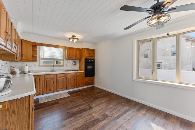 kitchen featuring a sink, black oven, light countertops, brown cabinets, and decorative backsplash