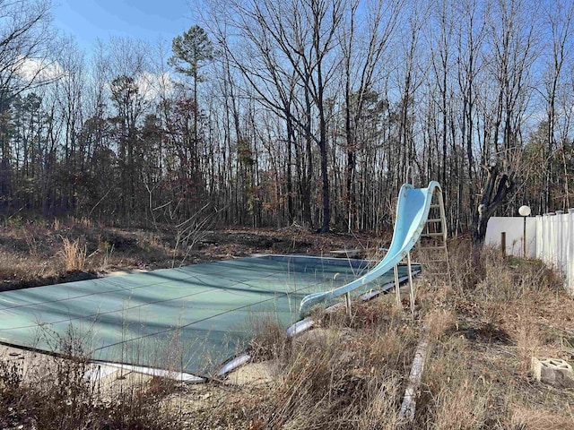 view of pool with a water slide and fence