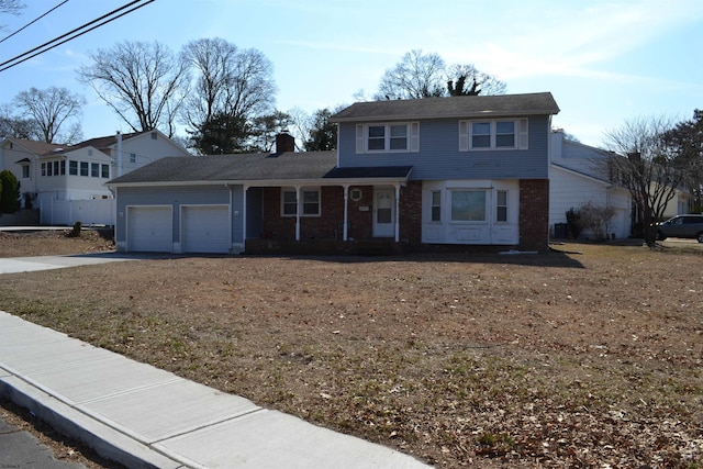 traditional home featuring concrete driveway, a chimney, and an attached garage