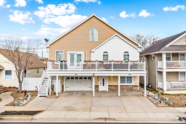 view of front of home with driveway, stone siding, an attached garage, and stairway