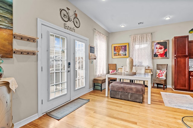 foyer entrance with light wood finished floors, french doors, visible vents, and baseboards