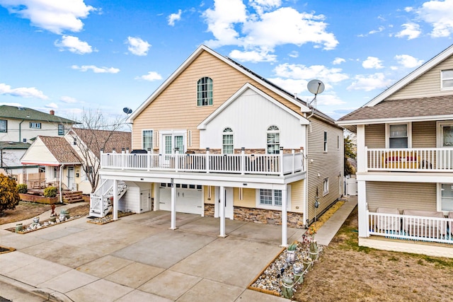 back of property with driveway, stone siding, and an attached garage