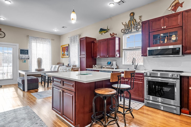 kitchen featuring appliances with stainless steel finishes, light countertops, light wood-style floors, and dark brown cabinets