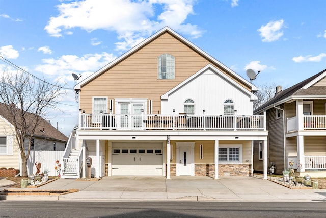 view of front of home with driveway, a garage, stone siding, stairway, and covered porch