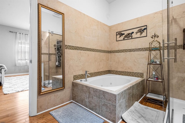 bathroom featuring a jetted tub, a stall shower, and wood finished floors