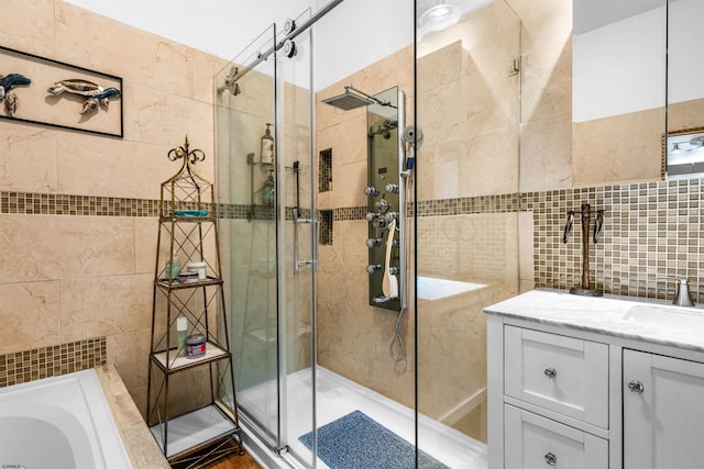 bathroom with tile walls, a shower stall, and vanity