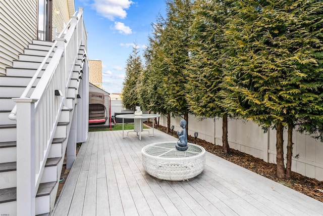 wooden terrace featuring outdoor dining area, a fenced backyard, and stairs