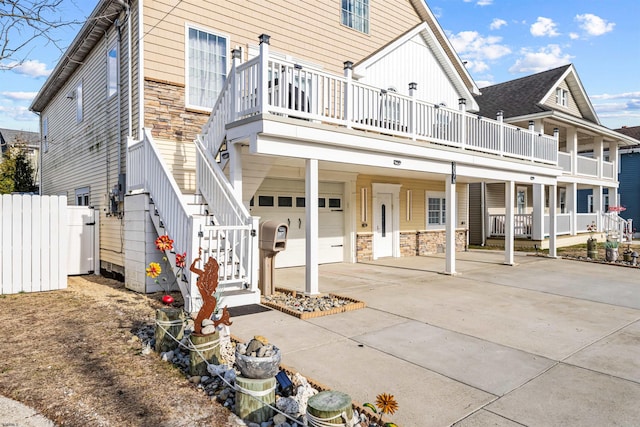 view of front of home featuring a garage, driveway, stone siding, stairway, and a carport