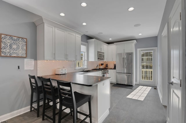 kitchen featuring stainless steel appliances, a peninsula, a sink, and decorative backsplash