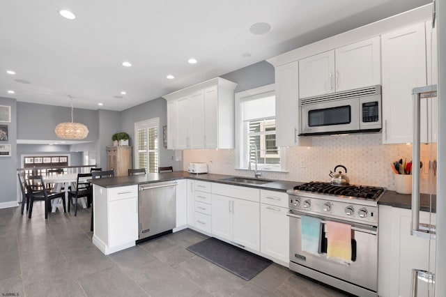 kitchen with dark countertops, a wealth of natural light, stainless steel appliances, and a sink