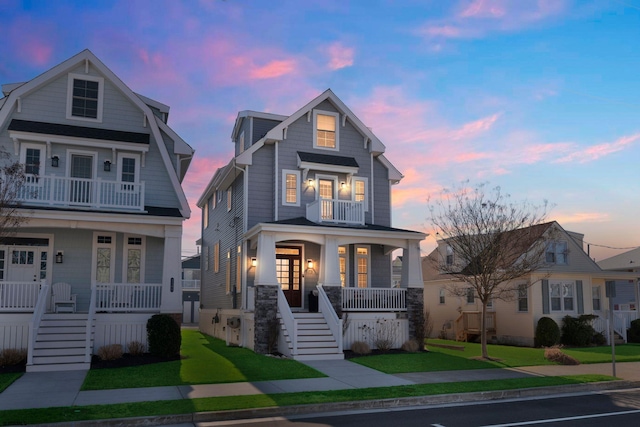 view of front of property featuring a balcony, a porch, stairway, french doors, and a front lawn