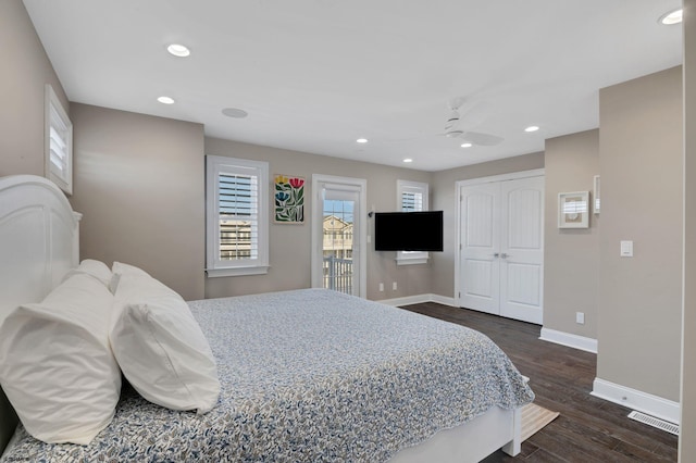 bedroom with dark wood-style floors, multiple windows, visible vents, and baseboards