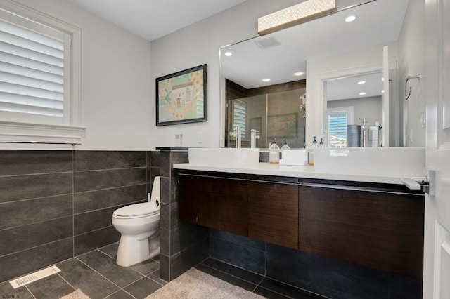 bathroom with a shower stall, visible vents, tile walls, and tile patterned floors