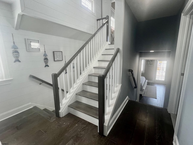 staircase with wooden walls, baseboards, and wood finished floors