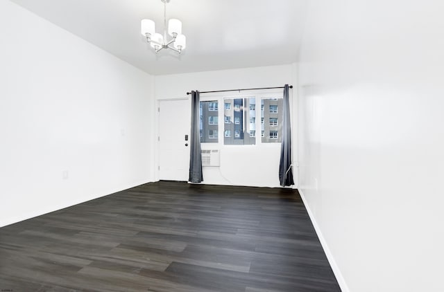 spare room with baseboards, a chandelier, and wood finished floors