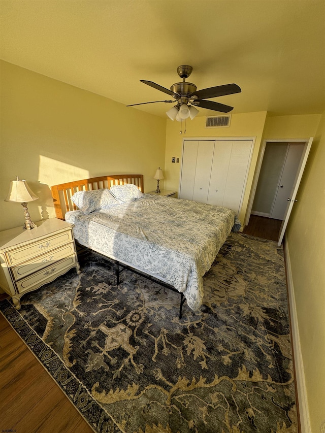 bedroom with a closet, visible vents, a ceiling fan, wood finished floors, and baseboards