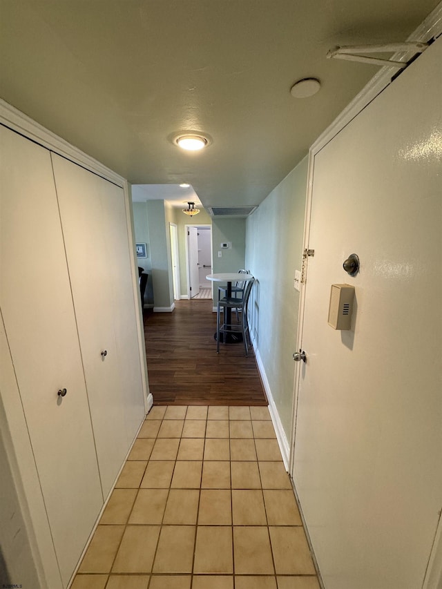 hall featuring light tile patterned floors and baseboards