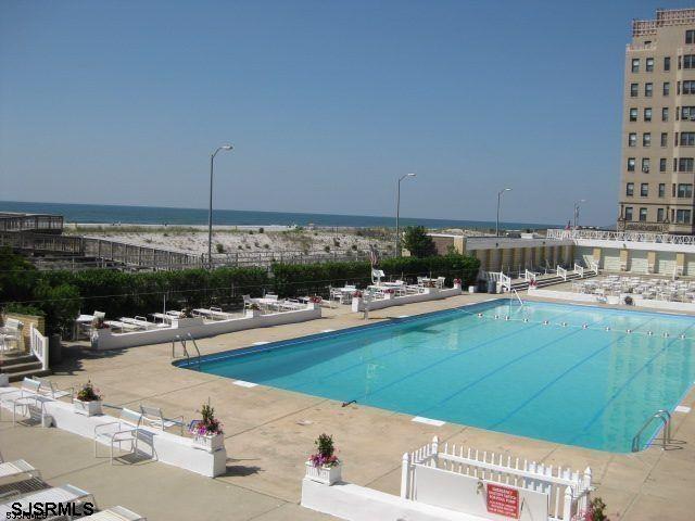 pool featuring a patio area, fence, and a water view