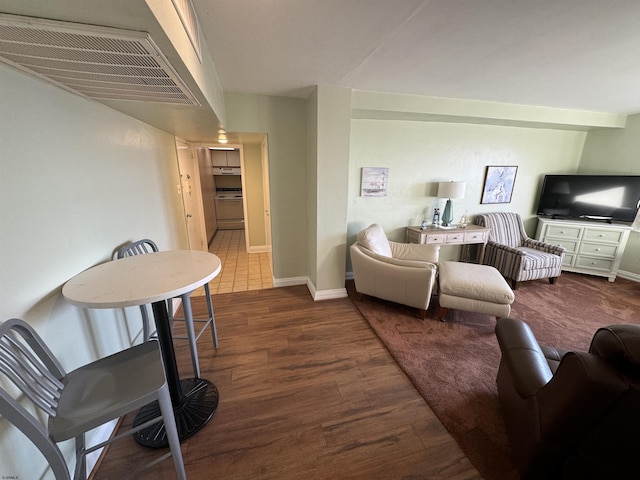 living area with wood finished floors, visible vents, and baseboards