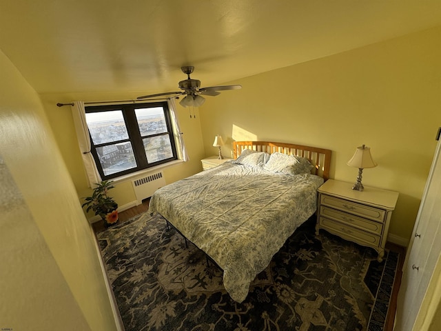 bedroom with radiator, a ceiling fan, baseboards, and wood finished floors