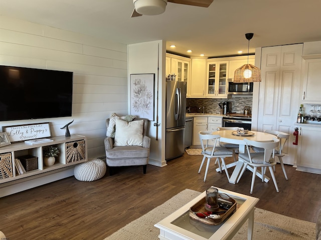 interior space with dark wood-style floors, stainless steel appliances, glass insert cabinets, and decorative backsplash