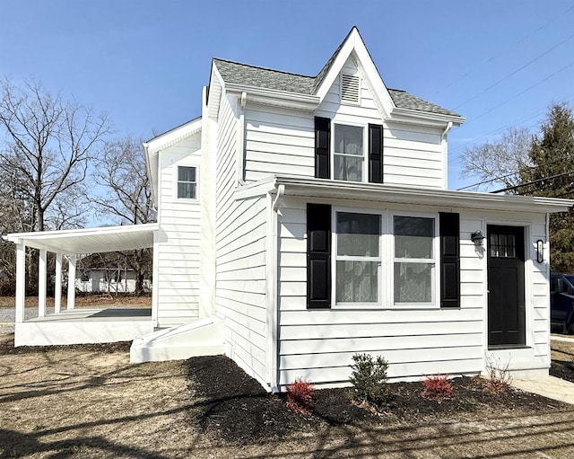 view of front of property with a carport, roof with shingles, and a patio area