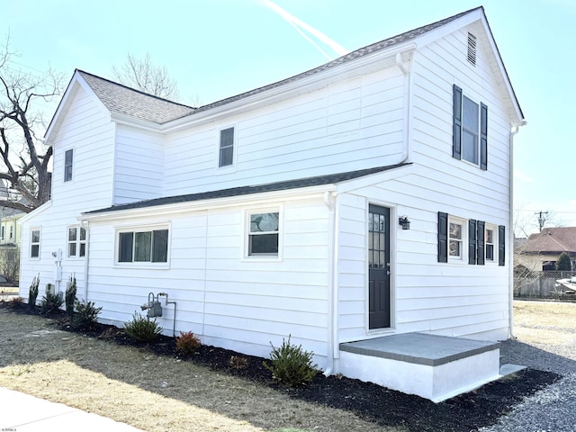 rear view of house featuring roof with shingles