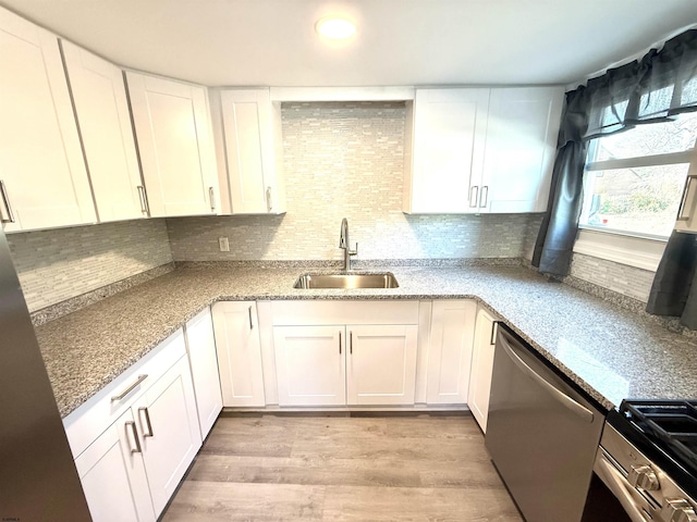 kitchen with light wood finished floors, white cabinetry, stainless steel appliances, and a sink