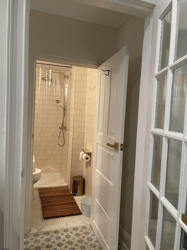 full bath featuring tile patterned flooring, a tile shower, and toilet