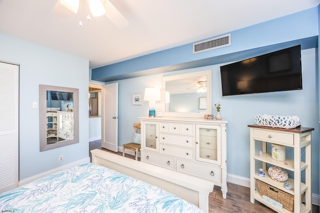 bedroom featuring a ceiling fan, visible vents, baseboards, and wood finished floors