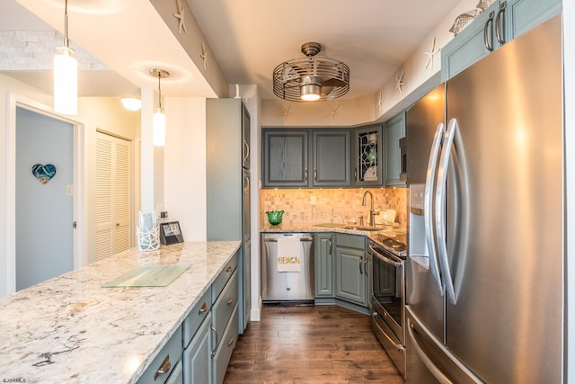 kitchen featuring light stone counters, stainless steel appliances, decorative backsplash, dark wood finished floors, and glass insert cabinets