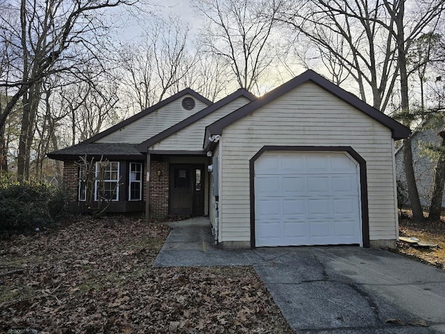 ranch-style house with driveway, brick siding, and an attached garage