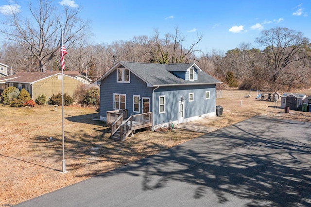 view of front facade featuring a deck, aphalt driveway, and roof with shingles