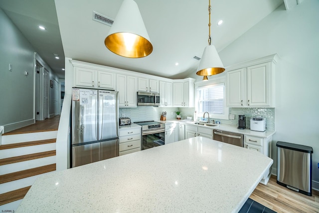 kitchen featuring stainless steel appliances, lofted ceiling, visible vents, white cabinets, and a sink