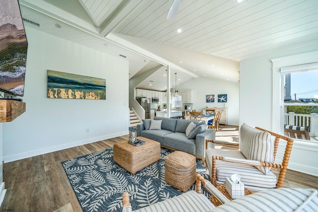 living room featuring vaulted ceiling with beams, recessed lighting, wood finished floors, baseboards, and stairs