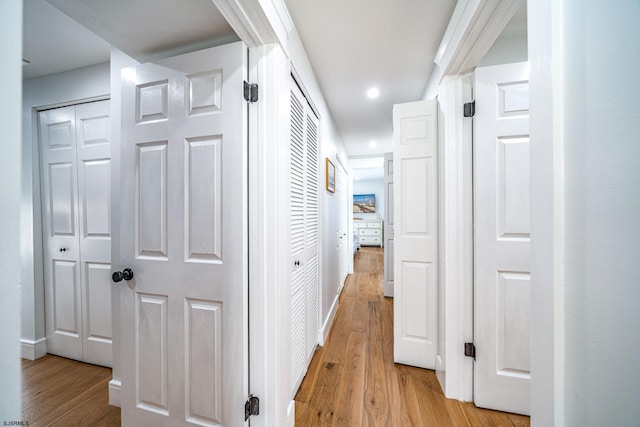 hall featuring light wood-type flooring, baseboards, and recessed lighting