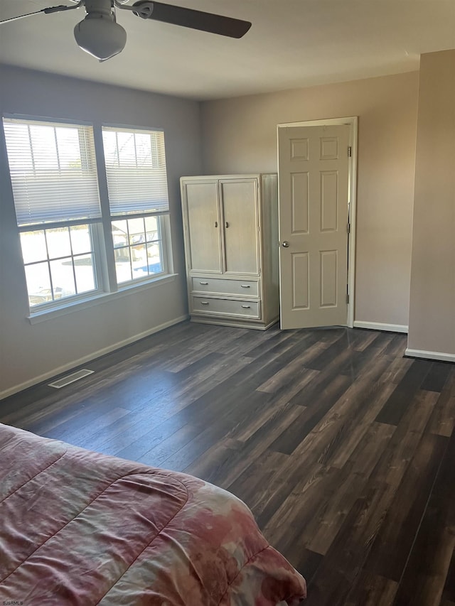 unfurnished bedroom featuring baseboards, visible vents, and dark wood finished floors