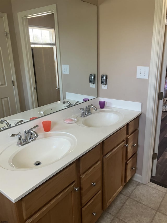 full bath featuring double vanity, a sink, and tile patterned flooring