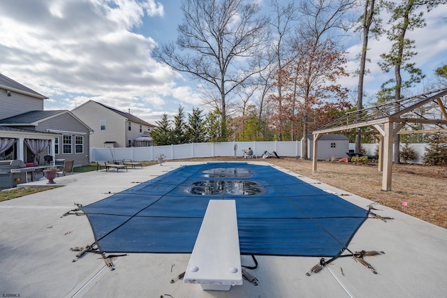 view of pool with an outbuilding, a fenced in pool, a fenced backyard, and a diving board