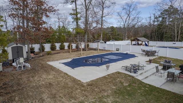 view of pool featuring a patio, a fenced in pool, a fenced backyard, a storage unit, and an outdoor structure