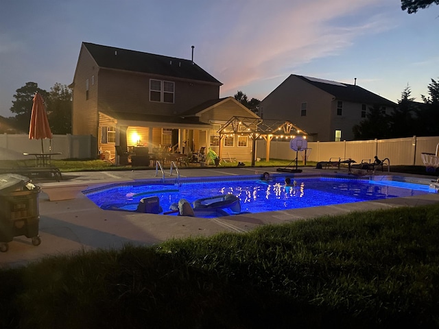 pool at dusk with a fenced backyard, a fenced in pool, and a patio area