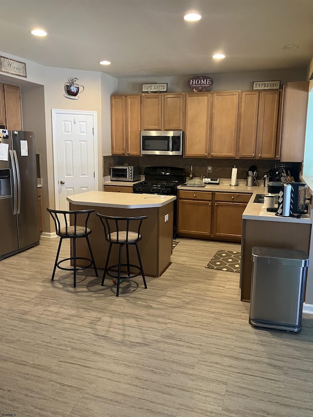 kitchen featuring a kitchen breakfast bar, light countertops, recessed lighting, stainless steel appliances, and brown cabinets