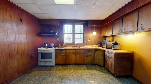 kitchen featuring a paneled ceiling, under cabinet range hood, white range with gas stovetop, a sink, and light countertops