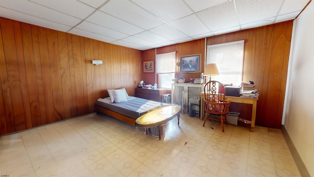 bedroom featuring radiator heating unit, wooden walls, a drop ceiling, and tile patterned floors