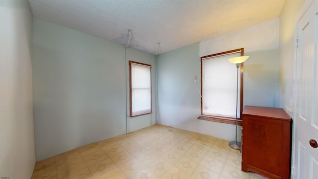 empty room with plenty of natural light and a textured ceiling