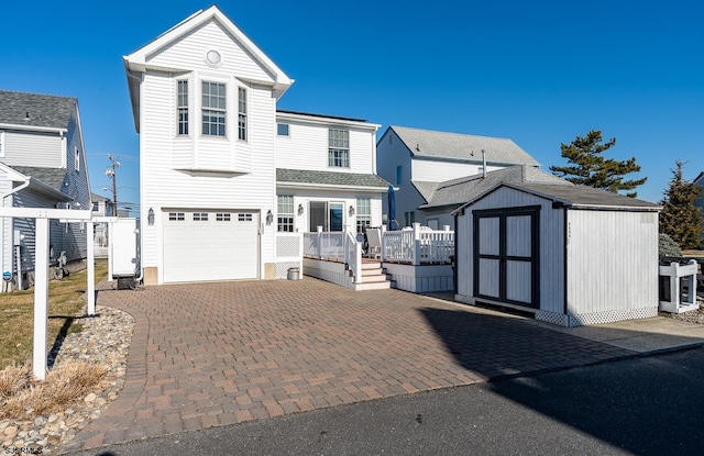 view of front of property with decorative driveway, fence, a shed, a garage, and an outdoor structure