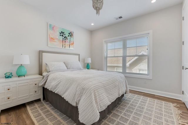 bedroom with recessed lighting, visible vents, baseboards, and wood finished floors