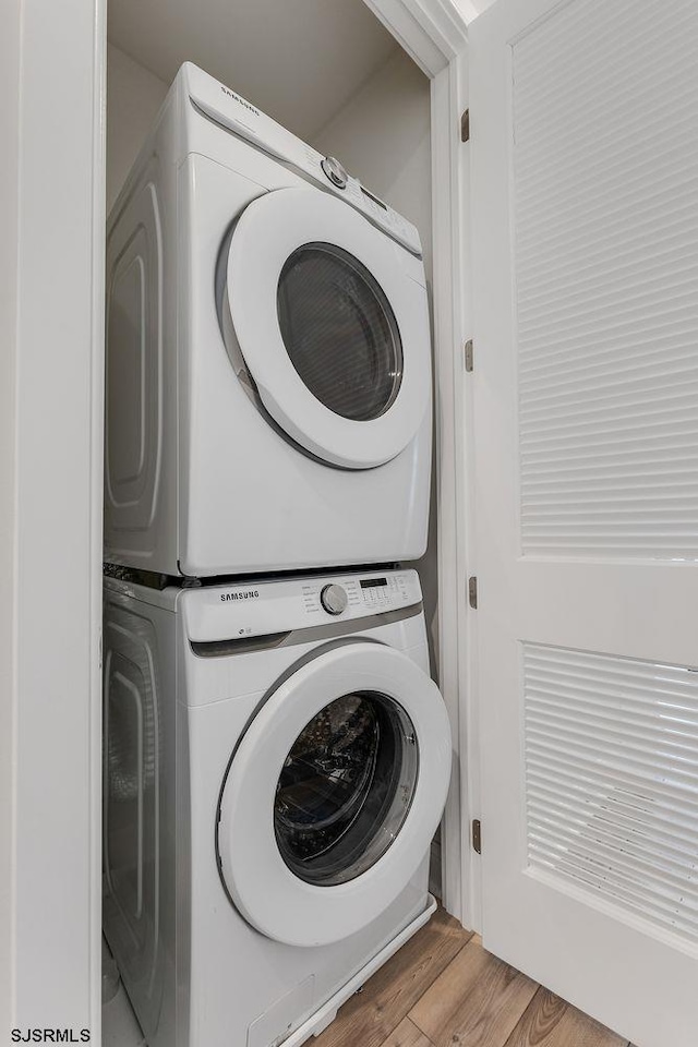 washroom featuring laundry area, light wood finished floors, and stacked washer / drying machine